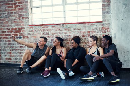 Photo for One last photo. a cheerful young group of people sitting down on the floor and taking a self portrait together in a gym - Royalty Free Image
