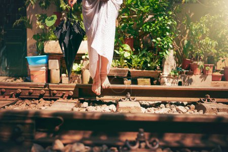 Téléchargez les photos : Les pieds ont été faits pour explorer. une femme marchant pieds nus sur les voies ferrées dans les rues du Vietnam - en image libre de droit