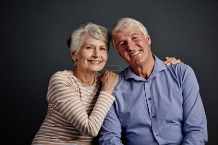 Téléchargez les photos : Amoureux, dans la vie. Portrait studio d'un couple de personnes âgées affectueux posant sur un fond gris - en image libre de droit