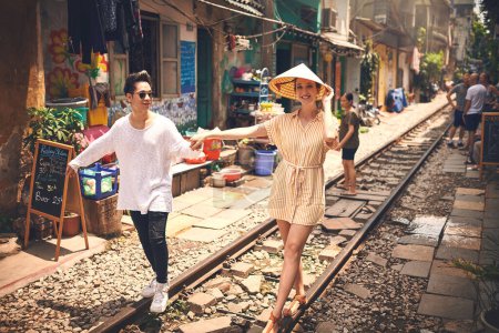 Foto de ¿Qué más necesitas que amor? una joven pareja caminando en las vías del tren a través de las calles de Vietnam - Imagen libre de derechos