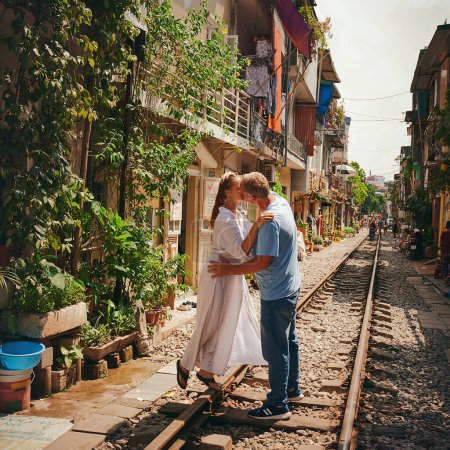 Foto de Siempre hay tiempo para un beso. una pareja feliz compartiendo un momento romántico en las vías del tren en las calles de Vietnam - Imagen libre de derechos