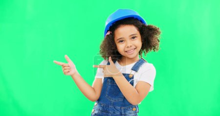 Photo for Kids, construction and a girl on a green screen background in studio pointing at building space. Children, architecture and design with a cute female child engineer wearing a hardhat on chromakey. - Royalty Free Image