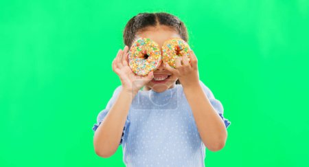 Photo for Donut on eyes, smile and child on green background with cake over face for funny, meme and comic. Food, excited kid and isolated happy girl with sweets, dessert treats and sugar doughnuts in studio. - Royalty Free Image