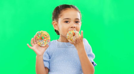 Photo for Candy, smile and child eating donuts on green background with cake for party, birthday and luxury. Food, excited kid and isolated happy girl with sweets, dessert treats and sugar doughnuts in studio. - Royalty Free Image