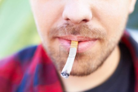 Photo for Cigarette, smoke and man with a tobacco habit and addiction due to unhealthy or bad lifestyle outdoor. Mouth, cancer and lips of young person or male smoker with substance or healthcare problem. - Royalty Free Image