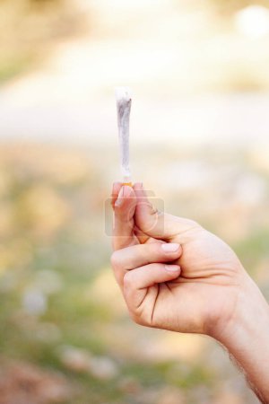 Photo for Marijuana, cannabis or hand with weed joint for a calm peace to relax or help reduce pain, stress or anxiety. Trippy, smoking or closeup of person showing a blunt for mental health benefits outdoors. - Royalty Free Image