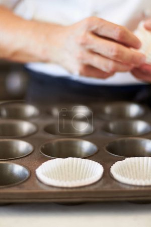 Photo for Cupcake tray, person hands and baking in kitchen with muffin wrapper and cooking closeup in bakery. Prepare, paper cup and food with chef in restaurant, coffee shop or cafe with sweet cake or pastry. - Royalty Free Image