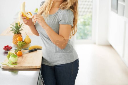 Photo for Fruit, peeling banana or woman with healthy morning snack, breakfast meal or lunch diet in home kitchen. Hands, body or vegan girl eating food to lose weight for wellness, vitamins or gut health. - Royalty Free Image