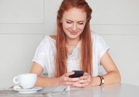 Photo for Coffee shop, phone and happy woman texting, relax and smile for chat app on wall background. Cafe, social media and female customer reading post, news or update while enjoying day off and tea break. - Royalty Free Image
