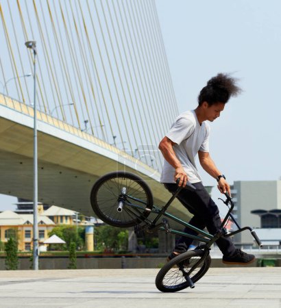 Photo for Boy, action and city with bicycle with trick or training with concrete for transportation. Cycling, outdoor and bmx with male hipster for fun and hobby with bridge and action for balance with stunt - Royalty Free Image