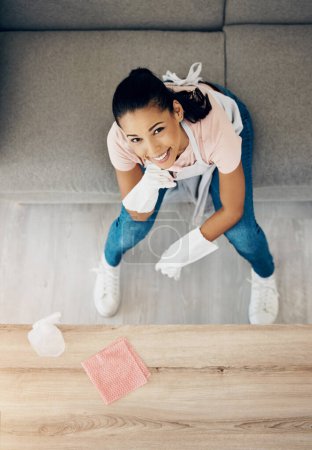 Photo for Happy, cleaning portrait and a woman in a house to clean with supplies, chemical and cloth. Above young female or cleaner in a lounge, apartment or room with a smile to polish wood or wipe dirt. - Royalty Free Image
