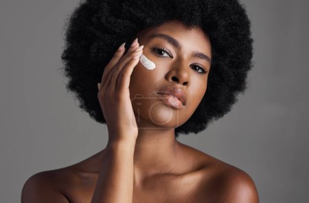 Photo for African woman, face cream and studio portrait with afro, skincare or cosmetic by grey background. Girl, model and healthy with natural glow on skin with makeup, clean aesthetic and product for beauty. - Royalty Free Image