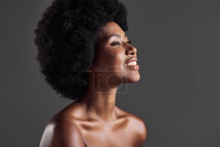 Foto de Cabello, sonrisa y perfil de mujer negra con peinado afro, belleza y cuidado de la piel sobre fondo gris. Cuidado del cabello, cosméticos y hermosa cara de modelo africano feliz con brillo y brillo de la piel en el estudio - Imagen libre de derechos