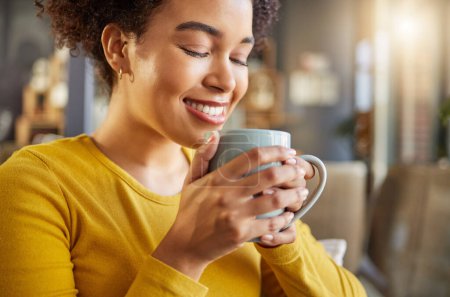 Foto de Mujer africana, taza de café y feliz en el sofá, aroma o energía para comenzar la mañana en el apartamento. Chica, sonrisa y bebida caliente para relajarse con coco, matcha o espresso para la fragancia, pensamiento y taza en casa. - Imagen libre de derechos