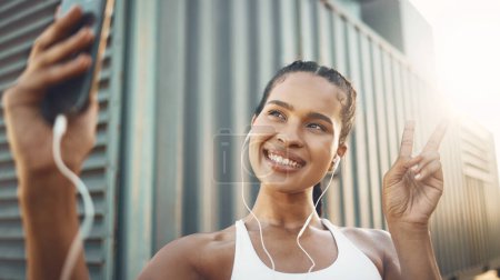Photo for Fitness, selfie or happy woman in city with peace sign listening to music or radio in sports exercise. Mobile photography, smile or girl athlete runner taking pictures in training workout outdoors. - Royalty Free Image