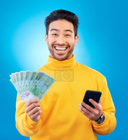 Photo for Man, phone and money fan in studio with prize, esports gambling or happy in portrait by blue background. Young asian guy, winner and cellphone with cash, fintech or crypto with profit, bonus or goals. - Royalty Free Image