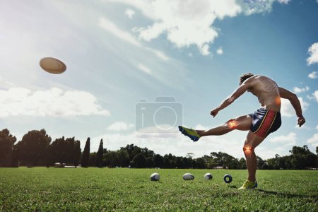 Téléchargez les photos : Homme, terrain et coup de pied ballon de rugby pour le sport avec lueur rouge, genou et blessure sur herbe avec douleur pour la forme physique. Athlète gars, superposition pour les douleurs articulaires, la puissance et l'entraînement pour le concours, la concurrence et le développement. - en image libre de droit