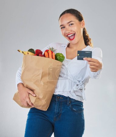 Photo for Credit card, portrait and woman grocery shopping online for fruits in studio isolated on a white background. Sustainable bag, food and excited customer with digital money, ecommerce and fintech sales. - Royalty Free Image