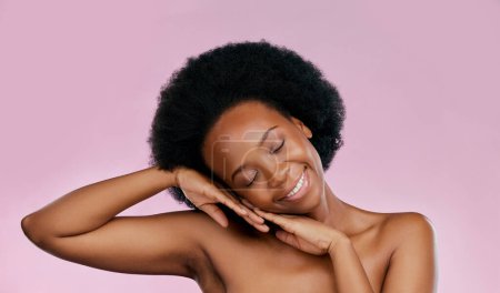 Téléchargez les photos : Détendez-vous, soins de la peau ou heureuse femme noire avec lueur de dermatologie, cosmétiques de salon ou bien-être. Sourire, les mains ou le visage d'un modèle africain avec la beauté ou l'amour-propre isolé sur un fond rose en studio. - en image libre de droit