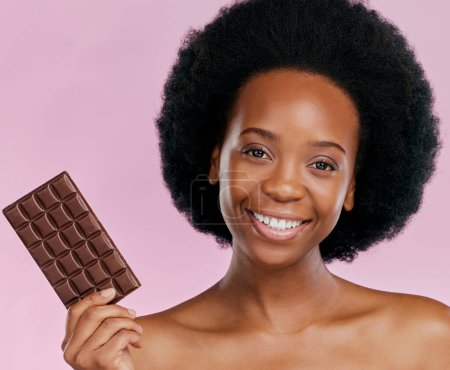 Téléchargez les photos : Portrait, chocolat et femme noire avec un sourire, beauté naturelle et dessert sur fond de studio. Visage, femme ou modèle jamaïcain avec bonbons, bonbons au cacao ou délicieuse collation avec friandise au sucre. - en image libre de droit