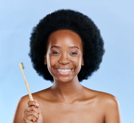 Foto de Cara, cepillo de dientes de bambú y sonrisa de mujer negra en un estudio aislado sobre un fondo azul. Retrato, cepillado de dientes y modelo con madera natural, ecológica o saludable para odontología, limpieza o higiene - Imagen libre de derechos