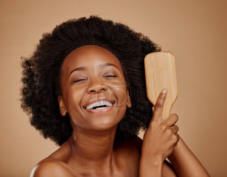 Foto de Mujer negra feliz, cepillo y cuidado del cabello en estudio, fondo marrón y tratamiento de textura rizada. Belleza natural, sonrisa y cara de peine de modelo femenino africano joven peinado limpio, saludable o afro. - Imagen libre de derechos