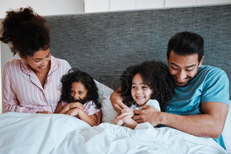 Photo for Love, bonding and children laying with their parents in their bedroom playing, tickling and laughing. Happy, smile and girl kids being playful and relaxing with their mother and father in the bedroom. - Royalty Free Image