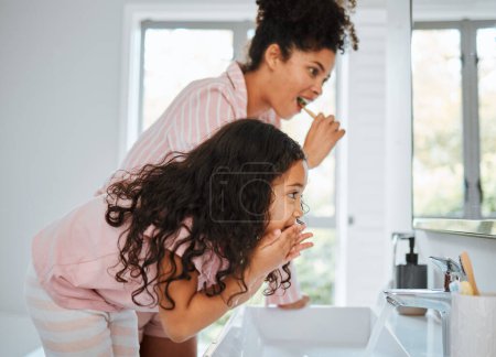 Foto de Mamá, niña limpiando los dientes y juntos en el baño con cepillo de dientes, pasta de dientes y rutina de la mañana en el hogar familiar. Niño, madre y diente de cepillado para la higiene, el aseo y la enseñanza de un cuidado dental saludable. - Imagen libre de derechos