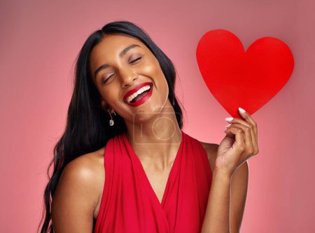 Photo for Funny, heart and valentines day with a woman on a pink background in studio for love or romance. Smile, emoji and social media with a young female comic holding a shape or symbol of affection. - Royalty Free Image