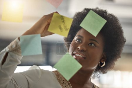 Photo for Black woman, writing or entrepreneur brainstorming ideas on glass board with startup strategy in office. Face, sticky notes or businesswoman planning a schedule, timeline or tasks for company growth. - Royalty Free Image