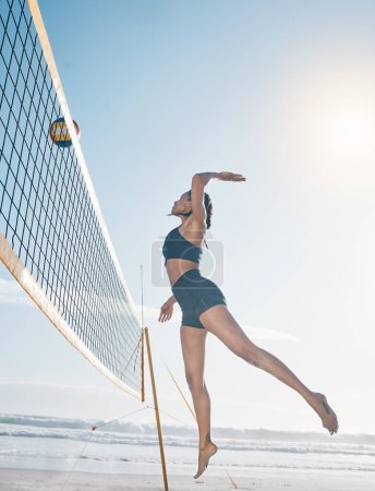 Téléchargez les photos : Femme, saut et joueur de volley-ball sur la plage au filet dans un match sportif sérieux, un match ou une compétition. Fit, active et sportive femme sautant ou atteignant pour le ballon dans la volée ou de pointe par la côte de l'océan. - en image libre de droit