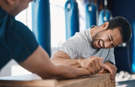 Photo for Strength, motivation and men arm wrestling in a gym on a table while being playful for challenge. Rivalry, game and male people or athletes doing strong muscle battle for fun, bonding and friendship - Royalty Free Image