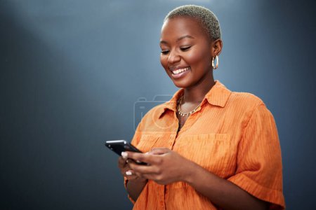 Foto de Teléfono, mensajes de texto y feliz mujer negra en el estudio para las redes sociales, aplicación o comunicación sobre fondo gris. Smartphone, búsqueda y sonrisa femenina africana para meme, post o en línea citas notificación. - Imagen libre de derechos
