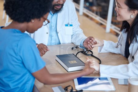 Photo for Hands, bible and a medical team praying during a meeting in a hospital office together. Medical, trust or teamwork with doctors and nurses asking God or Jesus for miracle help in a health clinic. - Royalty Free Image