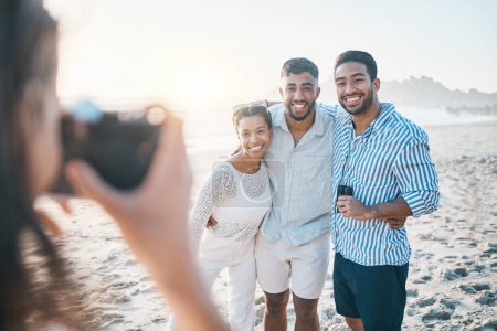 Photo for Happy, photo and friends at the beach with a photographer for summer memory, holiday or bonding. Smile, camera and a woman taking a picture of a group of people at the ocean during a vacation. - Royalty Free Image