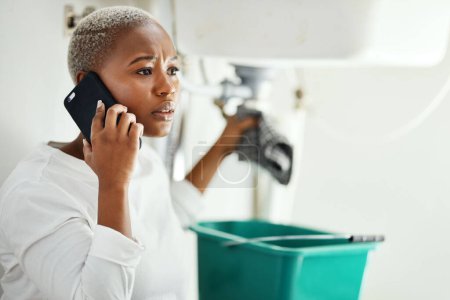 Téléchargez les photos : Appel téléphonique pour le service de plomberie, femme dans la salle de bain et l'aide de l'entrepreneur expert pour réparer la fuite. Stress, personne africaine sur téléphone portable et problème avec les tuyaux à la maison, des conseils professionnels pour l'entretien. - en image libre de droit