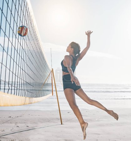 Photo for Woman, jump and volleyball on beach by net in serious sports match, game or competition. Body of female person jumping for ball in volley for spike, fitness or healthy wellness in exercise by ocean. - Royalty Free Image