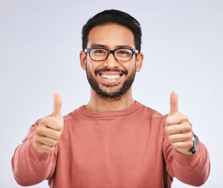 Photo for Thumbs up, portrait and man with glasses for success in studio, white background and winning news. Happy asian male model, ok emoji and like of feedback, review and vote yes in agreement of promotion. - Royalty Free Image