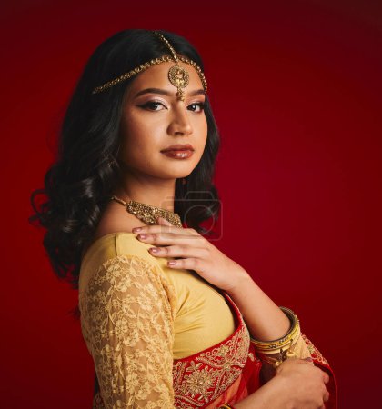 Photo for Fashion, culture and portrait of Indian woman with beauty in traditional clothes, jewellery and sari. Religion, Hindu and face of female person on red background with accessory, cosmetics and makeup. - Royalty Free Image