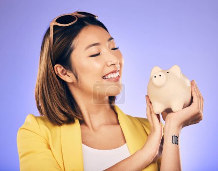 Photo for Piggy bank, finance and woman thinking of savings, investment and happy for money growth goals. Young asian person for financial management, money safe or banking security on studio purple background. - Royalty Free Image