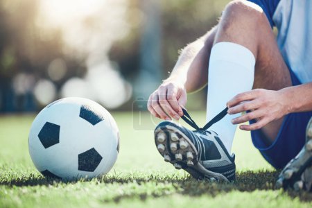 Photo for Ball, man and soccer player tie shoes for training, fitness games and performance on field. Closeup, football athlete and lace sneakers on feet, grass pitch and sports competition on stadium ground. - Royalty Free Image