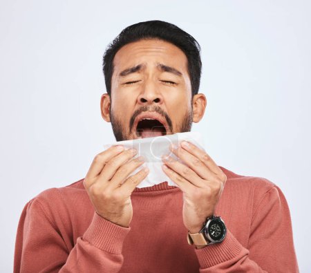 Téléchargez les photos : Allergie, éternuement et l'homme asiatique est malade avec des tissus en studio avec fond gris avec froid ou sinus. Virus, allergies et homme avec du papier hygiénique pour la grippe ou problème de nez ou de congestion - en image libre de droit