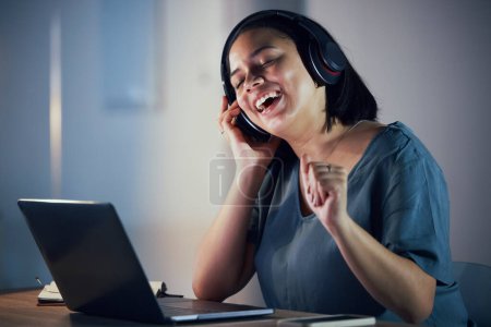 Photo for Happy woman, headphones and listening to music at night for online audio streaming on office desk. Female person or employee working late and enjoying sound track or songs on headset at the workplace. - Royalty Free Image