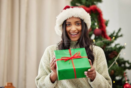 Foto de Navidad, retrato o chica feliz con una caja de regalo o regalo en una celebración navideña en casa en invierno. Adivinar, sonreír o emocionada mujer india con paquete con paquete festivo o de Navidad en una casa. - Imagen libre de derechos
