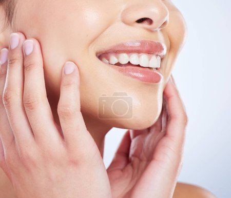 Photo for Skincare, smile and hands on face of woman in studio for healthy skin, glow or treatment on blue background. Happy, beauty and mouth of lady model with luxury hydration cosmetics, lip gloss or makeup. - Royalty Free Image