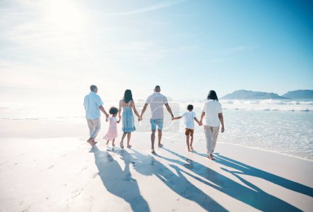 Foto de Viaje, playa y familia grande caminando de vacaciones juntos en el mar o en el océano uniéndose para el amor y la felicidad. Feliz, sol y padres con niños o niños y abuelos de vacaciones por la libertad. - Imagen libre de derechos