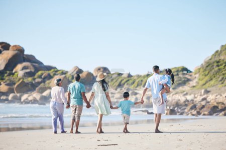 Photo for Beach, walking and grandparents, parents and children by sea for bonding, quality time and relax in nature. Family, travel and back of mom, dad and kids by ocean on holiday, vacation and adventure. - Royalty Free Image