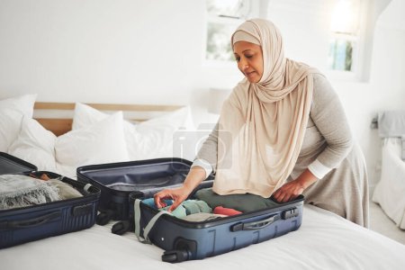 Foto de Viaje, dormitorio y mujer musulmana con maleta de embalaje para vacaciones, vacaciones y viaje religioso. Hogar, equipaje y mujer islámica con ropa en bolsa preparan para el viaje, la aventura y el turismo. - Imagen libre de derechos