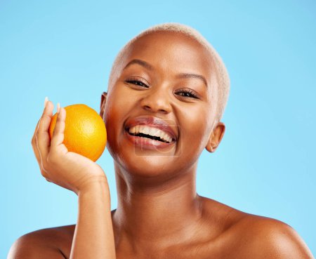 Photo for Orange, portrait and black woman with skincare, natural beauty and dermatology on a blue studio background. Female person, face detox or model with citrus fruit, cosmetics and wellness with vitamin c. - Royalty Free Image