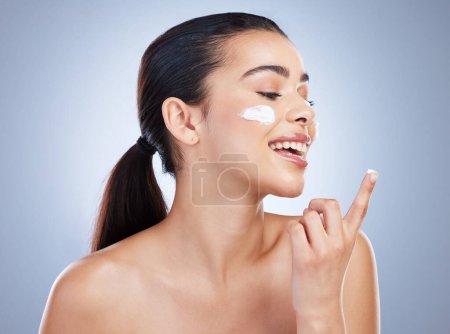 Photo for Skincare, hand and happy woman with face cream in studio or anti aging, collagen or hydration on grey background. Finger, smile and lady model with facial sunscreen, lotion or beauty mask application. - Royalty Free Image